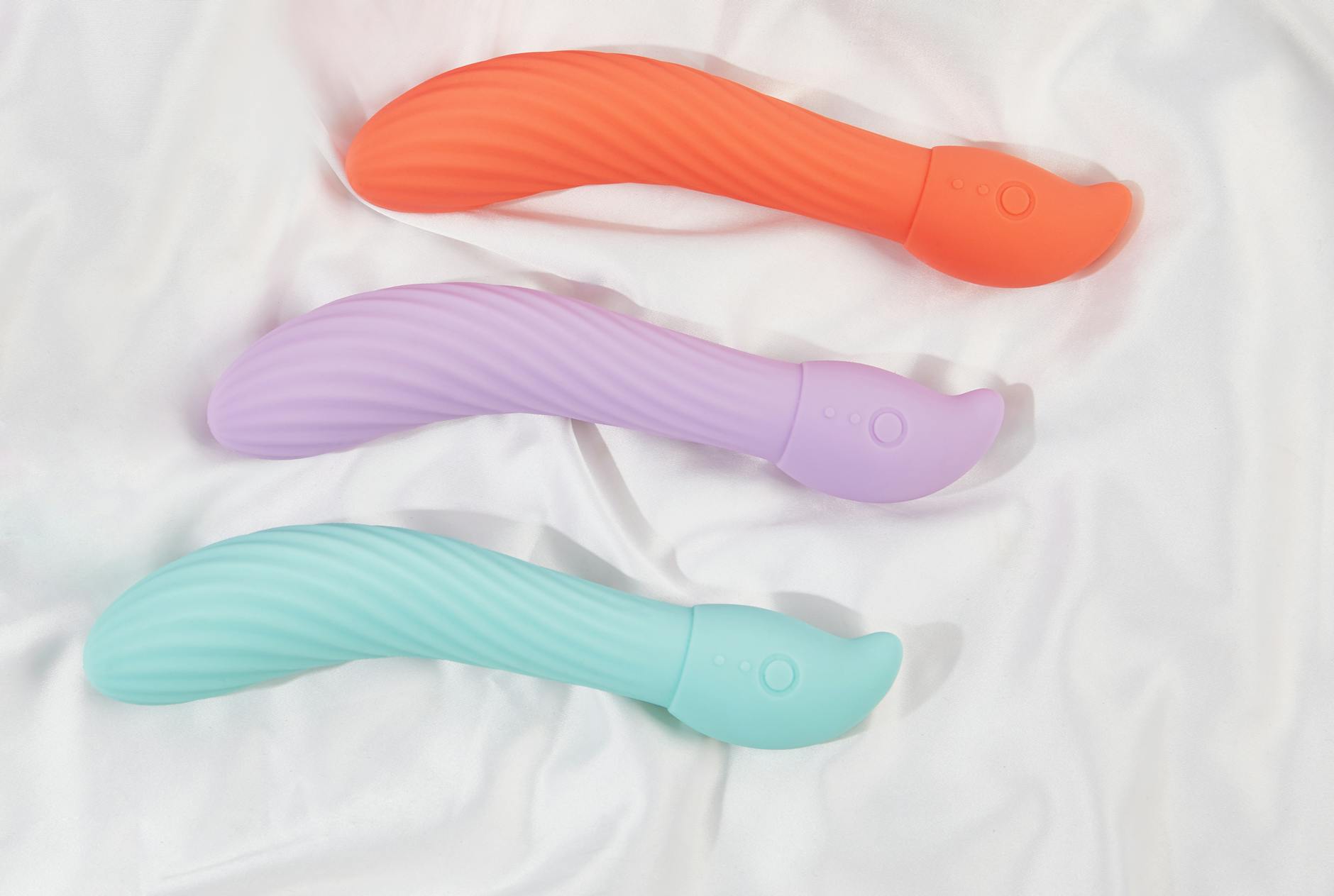 A sleek teal vibrator resting on white silk fabric, representing safe and mindful pleasure practices.