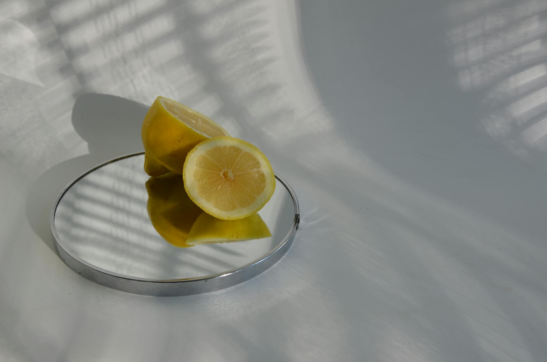 A hand holding a fresh lemon against a soft pink background, symbolizing gentle reconnection and self-care.
