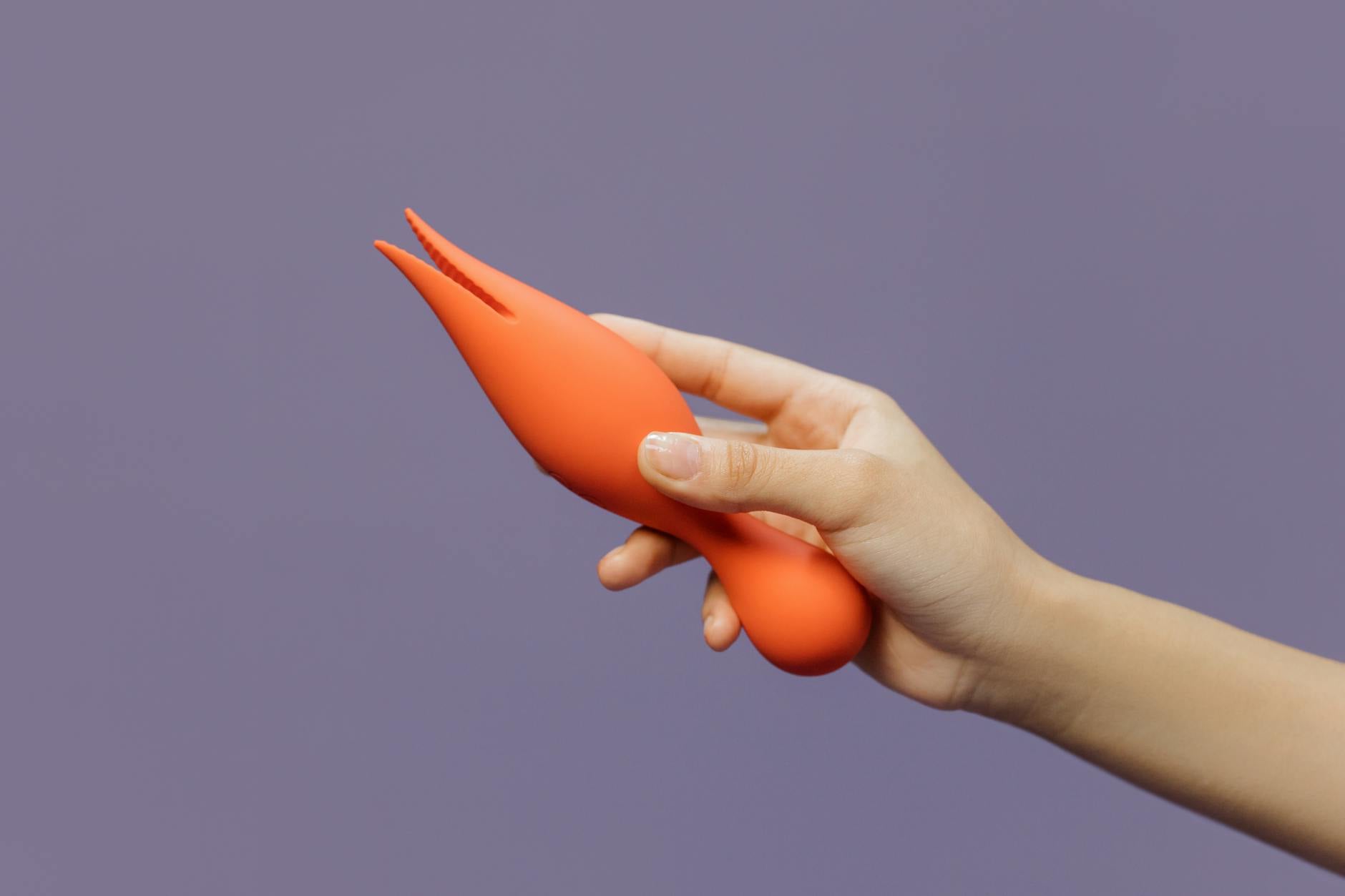 Hand holding a lemon vibrator against a minimalistic purple backdrop